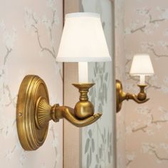 a wall light that is on the side of a wall with a white lamp shade