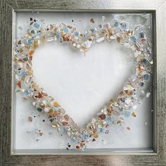 a heart made out of sea glass in a frame