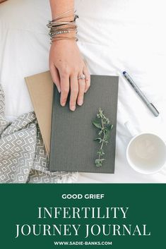 a person's hand resting on top of a book next to a cup of coffee