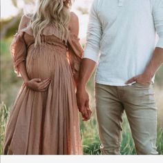 a man and woman holding hands while standing next to each other in a grassy field