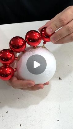 a person holding a white ball with red ornaments on it and some hands around it