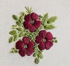 red flowers are embroidered onto a white cloth with green leaves and beads on the edges