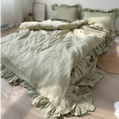 an unmade bed with ruffled sheets and pillows on the floor in front of a window