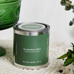 a green tin sitting on top of a white blanket next to a potted plant