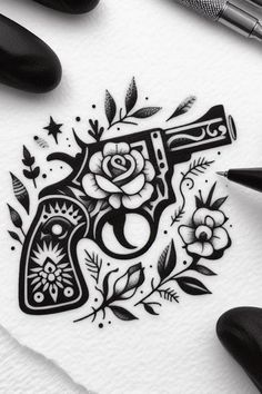 a drawing of a revolver with roses and stars on it, next to some pens