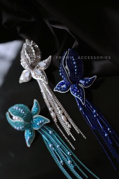 three different colored hair pins on a black cloth with blue and white flowers in the center