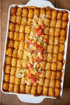 a square casserole dish filled with tater tots covered in toppings