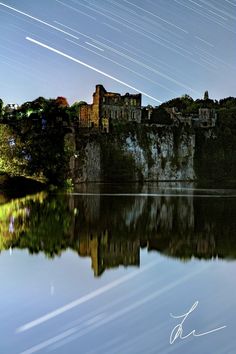 the night sky is reflected in the still water and stars are streaking across the sky