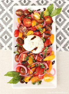 a white plate filled with lots of different types of vegetables on top of a table