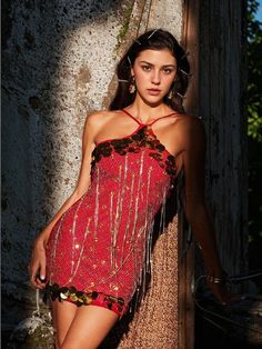 a woman in a red dress leaning against a tree