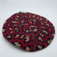 a red and black animal print rug on a white surface