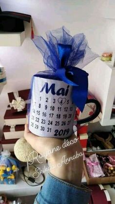 someone holding up a calendar coffee mug with a blue bow on it's head