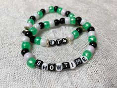 two bracelets with words on them that say show time and the word love is spelled in black, white, and green beads