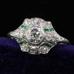 an old cut diamond and emerald ring on a velvet display case in a museum setting