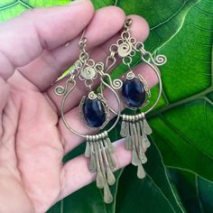 These hammered brass earrings were created by an artist in Morelos, Mexico. They feature hammered brass spiral flower designs with red obsidian stones on each earring. The hook is brass as well. The pieces from this workshop are meant to stand the test of time. All pieces can be returned to their original luster by being cleaned with a slice of lime. This is a 100% unique piece designed and handcrafted by our artist partner. This piece was ethically sourced directly from the artist, and the arti Wire Wrapped Brass Chandelier Earrings, Handmade Spiral Brass Earrings, Artisan Brass Chandelier Earrings As Gift, Artisan Brass Chandelier Earrings For Gift, Artisan Handmade Chandelier Earrings In Brass, Handmade Artisan Chandelier Earrings In Brass, Artisan Handmade Brass Chandelier Earrings, Bronze Bohemian Wire Wrapped Earrings, Bohemian Spiral Copper Earrings