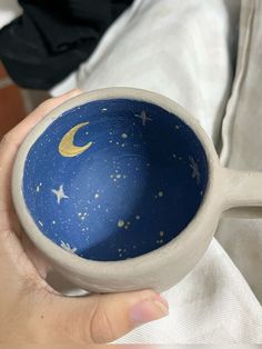 a hand holding a blue and white cup with stars and moon designs painted on it