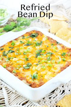 a white casserole dish filled with cheese and green onions next to tortilla chips