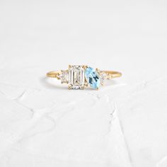 three stone diamond ring with blue topaz and white side stones in yellow gold setting