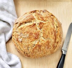 a loaf of bread sitting on top of a wooden cutting board next to a knife