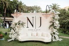 a white couch sitting in the middle of a lush green field with chandeliers hanging from it's sides