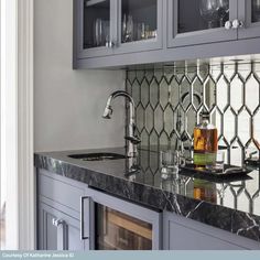 a kitchen with gray cabinets and marble counter tops, wine glasses on the cabinet doors