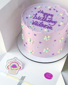 a pink birthday cake with purple frosting and blue sprinkles