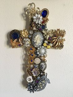 a cross made out of beads and other things hanging on the side of a wall