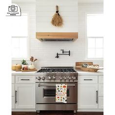 a stove top oven sitting inside of a kitchen next to a wooden counter top and white cabinets