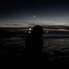 a person standing on the beach at night taking a photo with their cell phone in front of them