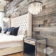 a bedroom with wooden walls and white bedding, chandelier hanging from the ceiling