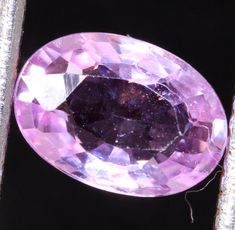 an oval shaped pink diamond sitting on top of a piece of metal