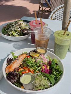 there is a large salad in the bowl on the table next to two cups with drinks