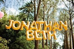 the words jonathan and beth are in front of some trees with balloons floating over them