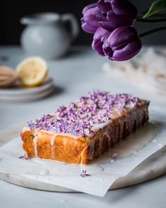 a piece of cake sitting on top of a white plate next to a purple flower