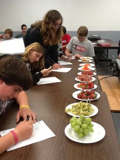 a group of people sitting around a table with plates of food on it and papers in front of them