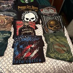 several t - shirts are laid out on a bed with an american flag and skull