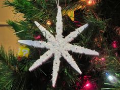 a white snowflake ornament hanging from a christmas tree