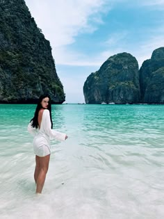 a woman standing in the water near some mountains