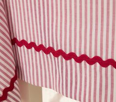 a red and white striped curtain with scalloped edges