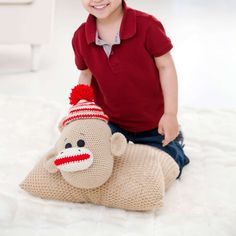 a little boy sitting on top of a stuffed animal wearing a knitted monkey hat