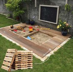 an outdoor area with wooden pallets and sand in the middle, surrounded by grass