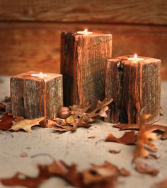 three wooden candles sitting on top of a table next to leaves and acorns