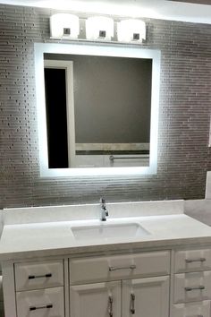 a bathroom with a large mirror above the sink and two lights on the wall behind it