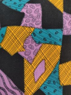 a close up view of a colorful tie on a black cloth with blue, yellow and purple designs