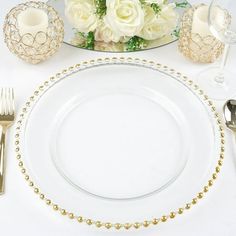 a white table setting with gold beaded place settings