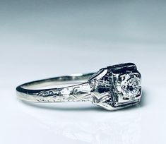 a white gold engagement ring with an old - fashioned style diamond center and filigrees