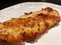 a piece of fried fish sitting on top of a white plate