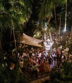 a group of people standing around each other in front of trees and lights at night