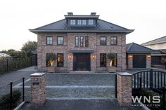 a large brick house with an iron fence and gated in area next to it