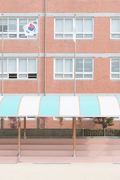 an empty parking lot in front of a brick building with blue and white awnings